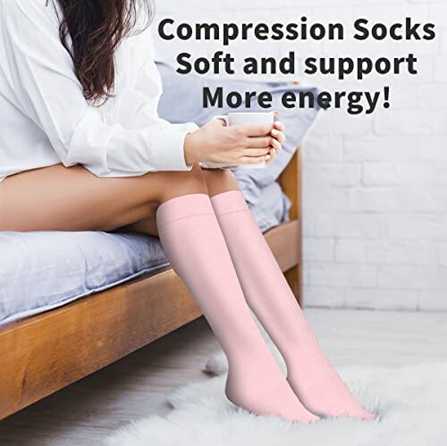 Person wearing pink compression socks sitting on a bed.